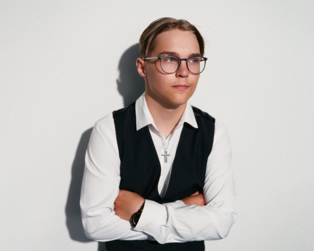 Rippikuvaus studiossa – nuori liivissä ja silmälaseissa ristiriipus kaulassa, Valokuvaamo KLIK Tampere